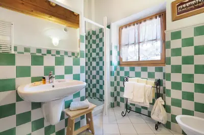 a bathroom with green and white tiled walls and a sink at Maso Vaia in Cavalese