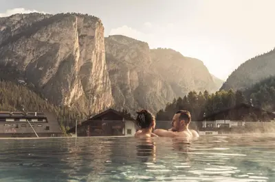 a man and woman in the water in the mountains at Hotel Continental Dolomites in Selva di Val Gardena