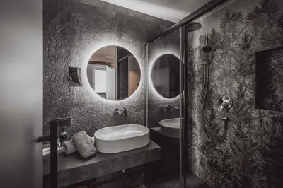 a bathroom with a sink and a shower with mirrors at Hotel Continental Dolomites in Selva di Val Gardena