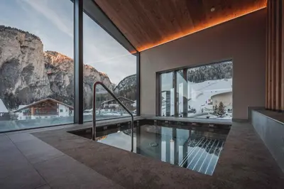 a house with a swimming pool with a mountain view at Hotel Continental Dolomites in Selva di Val Gardena