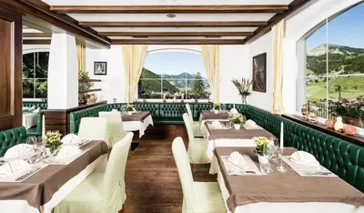 a restaurant with tables and chairs and a large window at Hotel Continental Dolomites in Selva di Val Gardena