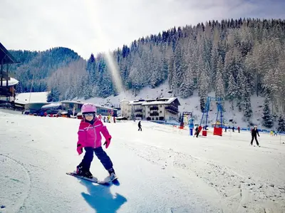 a young girl is skiing down a snow covered slope at Hotel Continental Dolomites in Selva di Val Gardena
