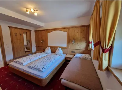 a bedroom with two beds and a window and curtains at Zollhof in Vipiteno