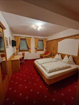 a hotel room with a bed and a desk at Zollhof in Vipiteno