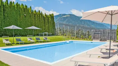 a swimming pool with chairs and an umbrella at Residence Ferienwohnungen Sonnegg in Vollan