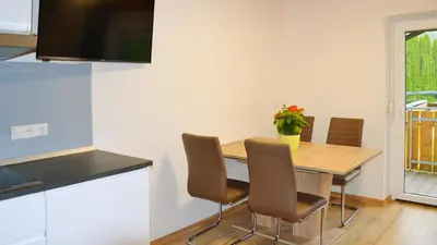 a kitchen with a table with chairs and a television at Residence Ferienwohnungen Sonnegg in Vollan