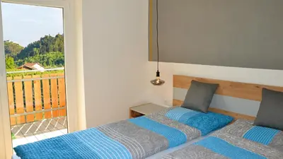 a bedroom with two beds and a balcony at Residence Ferienwohnungen Sonnegg in Vollan