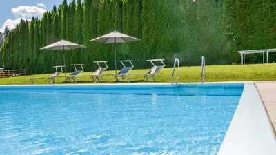 a group of chairs and umbrellas next to a swimming pool at Residence Ferienwohnungen Sonnegg in Vollan