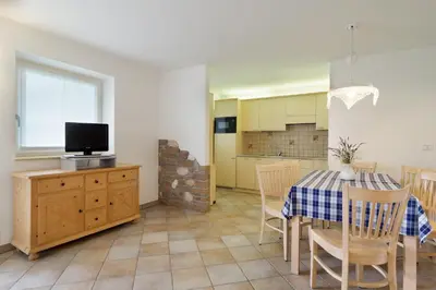 a kitchen and dining room with a table and a tv at Appartamento Boschetto Giulia in Carano