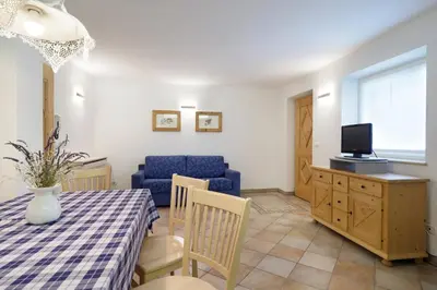 a living room with a table and a blue couch at Appartamento Boschetto Giulia in Carano