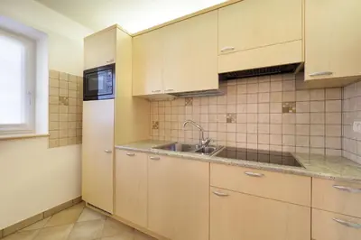 a kitchen with wooden cabinets and a sink at Appartamento Boschetto Giulia in Carano
