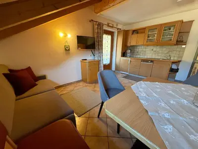 a living room with a table and a kitchen at Chalet Romy - AP Sasplat in Pramauron