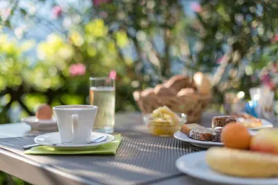 a table with a cup of coffee and plates of food at Garni Hotel Ritterhof in Termeno