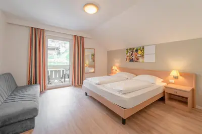 a large bedroom with a bed and a couch at Garni Hotel Ritterhof in Termeno