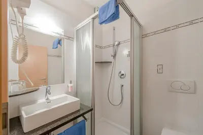 a white bathroom with a sink and a shower at Garni Hotel Ritterhof in Termeno