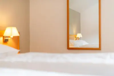 a bedroom with a mirror and a bed at Garni Hotel Ritterhof in Termeno