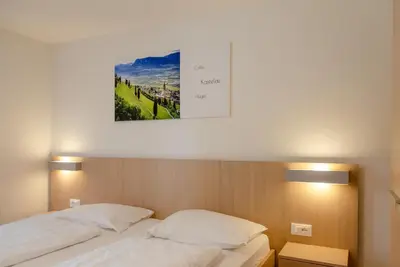 a bedroom with two beds and a picture on the wall at Garni Hotel Ritterhof in Termeno