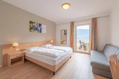 a bedroom with a bed and a couch and a window at Garni Hotel Ritterhof in Termeno