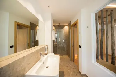 a bathroom with a sink and a mirror and a shower at Hotel Goldene Traube in Termeno