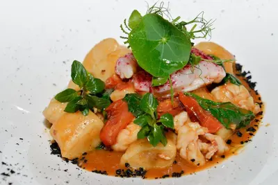 a plate of food with shrimp and greens on it at Hotel Goldene Traube in Termeno