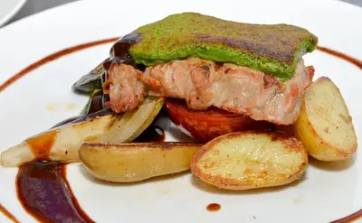 a plate of food with a piece of meat and potatoes at Hotel Goldene Traube in Termeno