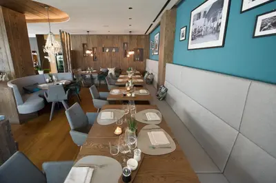 a restaurant with long wooden tables and chairs at Hotel Goldene Traube in Termeno