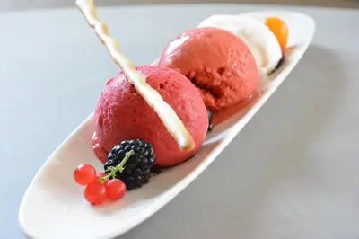 a white plate with red desserts on a table at Hotel Goldene Traube in Termeno