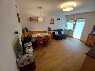 a kitchen and living room with a table and chairs at Cësa Valeria e Cësa Giulio in Campitello di Fassa