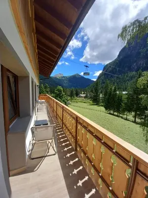 a balcony with chairs and a view of a mountain at Cësa Valeria e Cësa Giulio in Campitello di Fassa