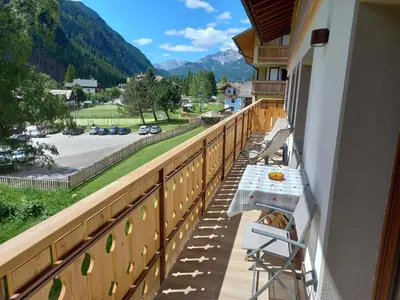 a balcony with chairs and a view of a parking lot at Cësa Valeria e Cësa Giulio in Campitello di Fassa