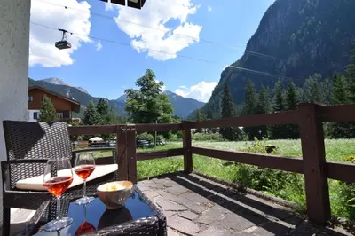 a table with wine glasses on a balcony with a view at Cësa Valeria e Cësa Giulio in Campitello di Fassa
