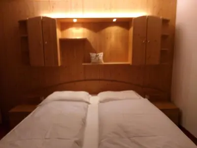 a bedroom with two beds and wooden cabinets at Hotel Schönwies in Trodena