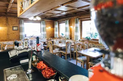 a restaurant with tables and chairs and a bar at Hotel Schönwies in Trodena