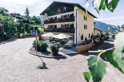 a large building with tables and umbrellas in a courtyard at Hotel Schönwies in Trodena