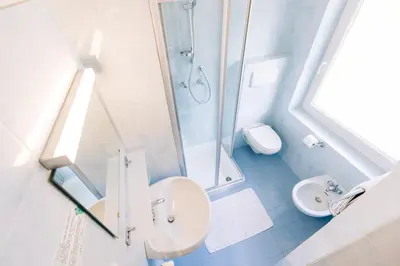 a bathroom with a shower and a sink and a toilet at Hotel Schönwies in Trodena