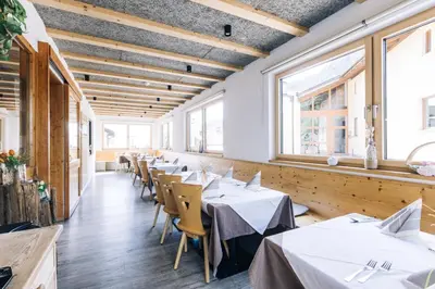 a row of tables in a restaurant with white tablecloths at Hotel Schönwies in Trodena