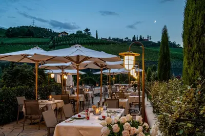 a restaurant with tables and umbrellas in a garden at Hotel Spitaler in Appiano sulla Strada del Vino