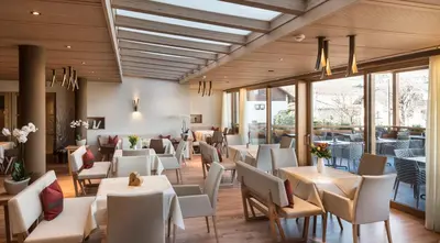 a restaurant with white tables and chairs and windows at Hotel Spitaler in Appiano sulla Strada del Vino