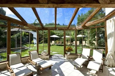 a conservatory with chairs and tables and windows at Hotel Spitaler in Appiano sulla Strada del Vino