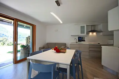 a kitchen and dining room with a white table and chairs at casa waldner in Castello di Fiemme
