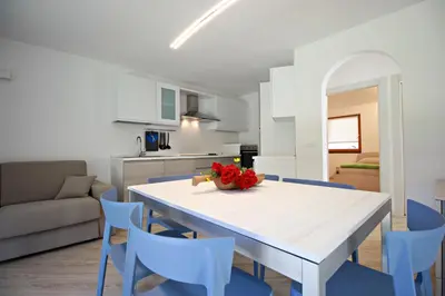 a kitchen and dining room with a white table and blue chairs at casa waldner in Castello di Fiemme