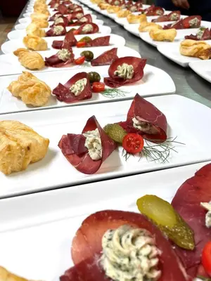 a row of white plates filled with different types of food at Hotel Am Wolfgrubenersee in Soprabolzano