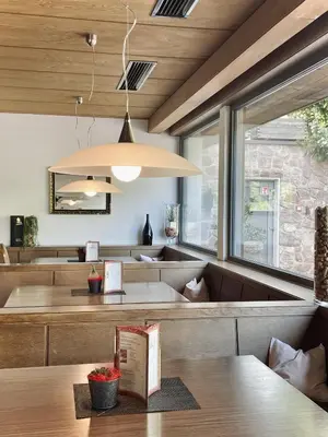 a dining room with a table and a large light fixture at Hotel Am Wolfgrubenersee in Soprabolzano