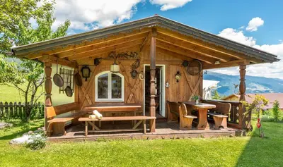 a small wooden cabin with a table and benches at Hotel Alpenfrieden in Maranza