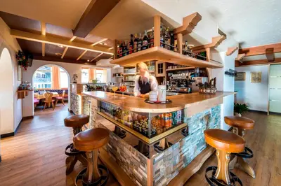 a woman standing at a bar in a restaurant at Hotel Alpenfrieden in Maranza