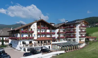 a large white building with balconies and cars parked in front at Hotel Alpenfrieden in Maranza