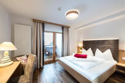a hotel room with a bed and a desk and a chair at Hotel Alpenfrieden in Maranza
