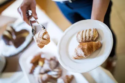 a person holding a plate with a plate of pastries at Hotel Masatsch in Caldaro