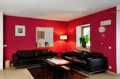 a living room with red walls and leather furniture at Hotel Masatsch in Caldaro