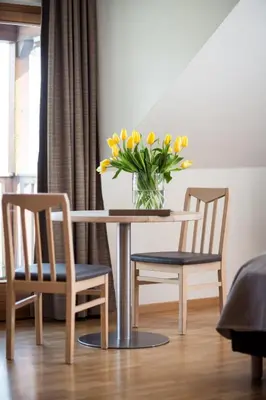 a table with two chairs and a vase of yellow flowers at Hotel Masatsch in Caldaro